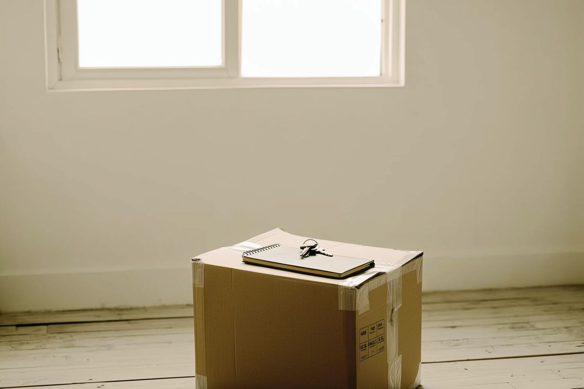 Gepackter Karton mit Notizbuch obenauf in einem leeren Zimmer